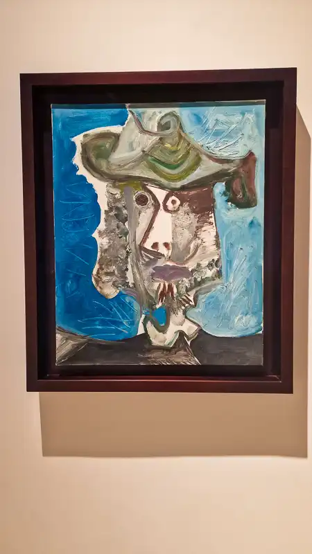 Portret mężczyzny w kapeluszu i kołnierzu, namalowany grubymi, dynamicznymi pociągnięciami pędzla (impasto). Twarz jest zniekształcona, a tło to jasny, elektryzujący niebieski.