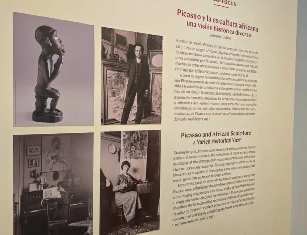 Tablica informacyjna z tekstem w języku hiszpańskim i angielskim (tytuł: "Picasso and African Sculpture: A Varied Historical View") oraz historycznymi zdjęciami. Widoczna jest tam afrykańska rzeźba i czarno-białe zdjęcia Picassa (m.in. stojący i siedzący).